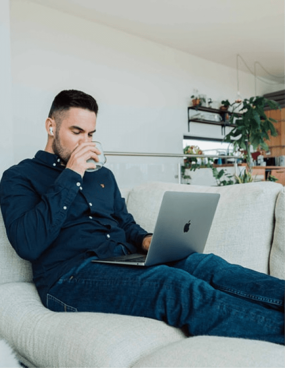 画像：飲み物を飲みながらパソコンを見る男性